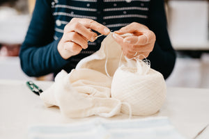 artisan hands knitting with white yarn