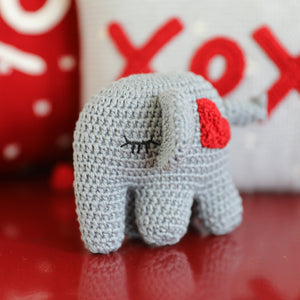 valentine gray elephant with red heart on red table with red and white pillows in background