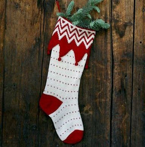 red and white christmas stocking stuffed with green pine against wooden background