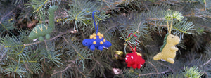 close up of 4 colorful dinosaur ornaments hanging on a christmas tree