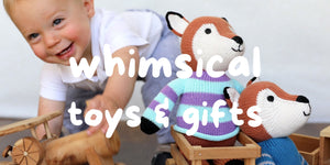 baby leaning down to grab wooden toys next to 2 knit fox in sweaters
